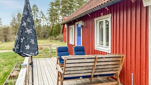 A red wooden building with a blue door, two blue chairs, and a wooden bench on a wooden deck. - Gorgeous home in Markaryd (Markaryd)