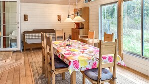 A wooden interior with a dining table set for four, surrounded by chairs with cushions. A bench and a small table with chairs are also visible. - Gorgeous home in Markaryd (Markaryd)