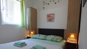 Ein Schlafzimmer mit einem Bett, zwei Nachttischen mit Lampen, einem Kleiderschrank und einem Blumenbild an der Wand.