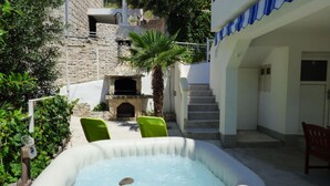 Ein Steinhaus mit Kamin, einem kleinen Pool und einer Treppe, die zu einer oberen Ebene führt.