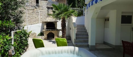 A stone building with a stone fireplace, a small pool, and a staircase leading to an upper level.