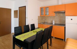 A compact kitchen with orange cabinets, a sink, and a stove. There is a dining table with chairs and a yellow tablecloth. - 3 bedroom stunning home in Mimice (Mimice)