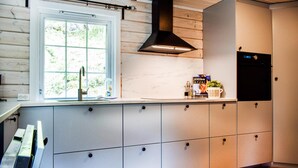 Une cuisine moderne dotée d’une fenêtre, d’une hotte noire et d’un four encastré.