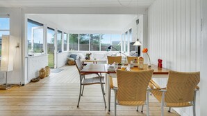A bright, open-plan living space with a wooden floor, white walls, and large windows. - Beautiful home in Slagelse with kitchen (Slagelse)