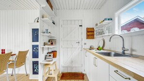 A compact kitchen with white cabinetry, a wooden countertop, and a window overlooking a red building. - Beautiful home in Slagelse with kitchen (Slagelse)