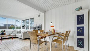 A bright, open-plan living and dining area with a white interior, wooden flooring, and large windows offering a view of the outdoors. - Beautiful home in Slagelse with kitchen (Slagelse)