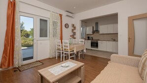 Un salon moderne comprenant un canapé, une table à manger avec des chaises et un coin cuisine avec des placards et des appareils électroménagers.