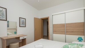 Une chambre moderne comprenant un lit, un bureau, une chaise, une armoire et un miroir.