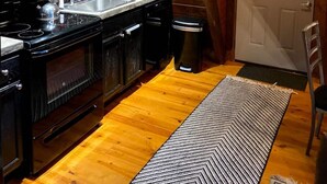 A kitchen with wooden cabinets, a microwave, stove, sink, and a trash bin. - HOT TUB,  Unique A-Frame Cabin, Walk to ski resort (Mars Hill)