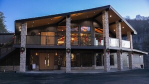 A multi-story building with a stone facade, large windows, and a balcony. - HOT TUB,  Unique A-Frame Cabin, Walk to ski resort (Mars Hill)