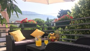 A balcony with wicker furniture, a table with a pitcher of orange juice, and a bowl of fruit. - Sunflower-beautiful Modern Apt. w. Terrace&garden (Kastela)
