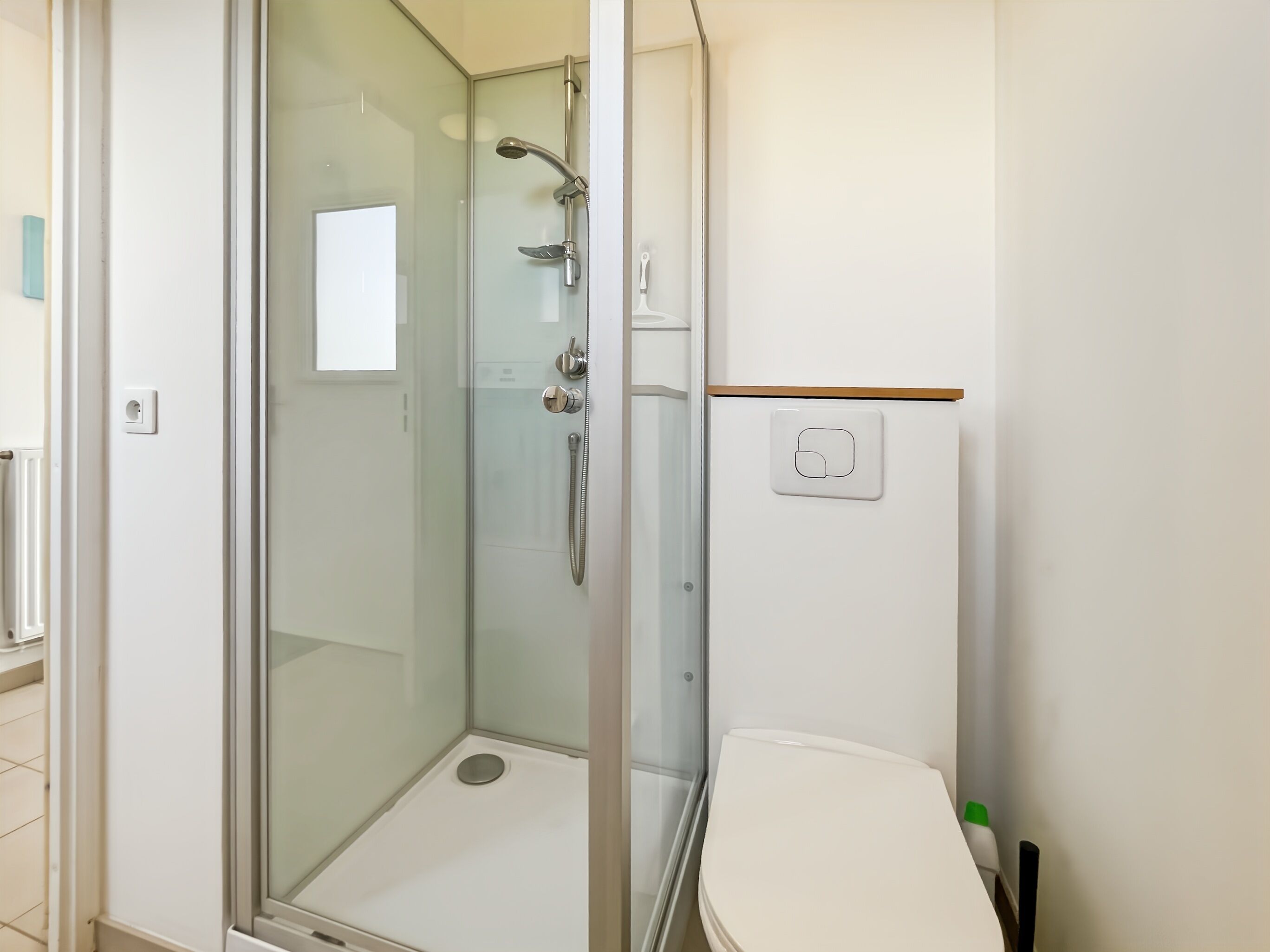 A modern bathroom with a glass-enclosed shower, a white toilet, and a small sink.
