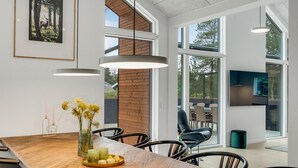 A modern dining area with a wooden table, chairs, and pendant lights. - Lovely home in Blåvand with sauna (Blåvand)
