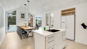 A modern kitchen with a large island, white cabinetry, and a built-in refrigerator. - Lovely home in Blåvand with sauna (Blåvand)