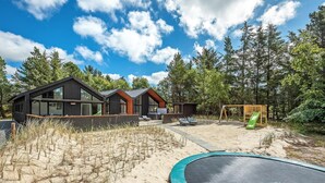 A modern house with large windows, a swimming pool, and a trampoline in a natural setting. - Lovely home in Blåvand with sauna (Blåvand)