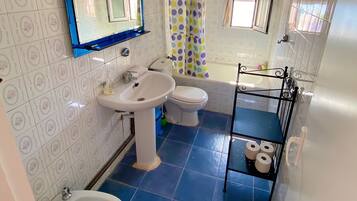 Een bad/douchecombinatie, een haardroger, een bidet, handdoeken