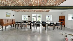 A spacious room with a brick ceiling, a long wooden table with chairs, and large windows providing natural light. - 7 bedroom stunning apartment in Varde (Varde)