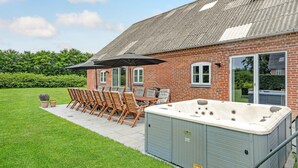 A brick house with a patio area featuring a hot tub, outdoor furniture, and a large umbrella. - 7 bedroom stunning apartment in Varde (Varde)