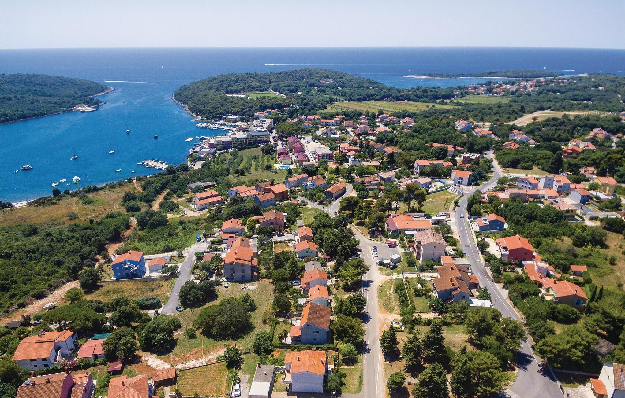 An aerial view of a coastal town with residential buildings, roads, and a marina.