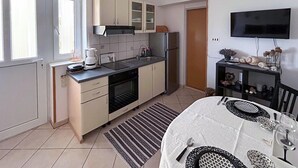 Une cuisine moderne avec un coin repas, équipée d’un téléviseur à écran plat, d’un réfrigérateur et d’une machine à café.