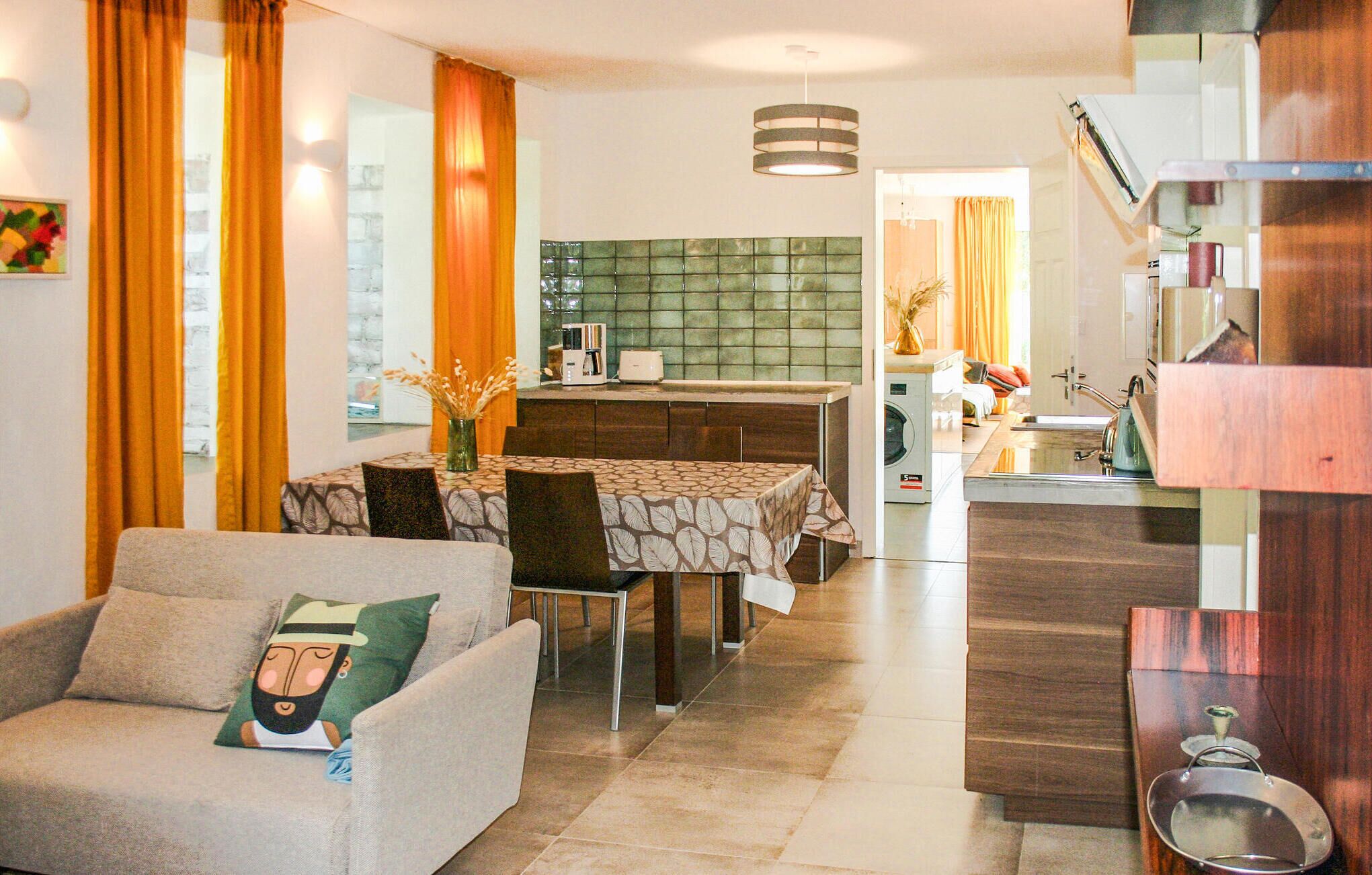 Una sala de estar moderna con un sofá, una mesa de comedor y una cocina al fondo.