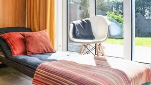Una habitación moderna con un sofá, una silla y un ventanal grande.