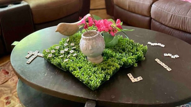 A living room with two brown leather sofas, a round coffee table with a green mat, a vase with pink flowers, and scattered Scrabble tiles. - Modern 4 Bedroom pets welcome sleeps 8 (Greensboro)
