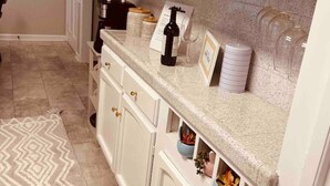 A kitchen with white cabinets, a clock on the wall, and a patterned rug on the floor. - Modern 4 Bedroom pets welcome sleeps 8 (Greensboro)
