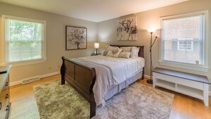 A bedroom with a bed, bedside tables, a bench, and artwork on the walls. - Modern 4 Bedroom pets welcome sleeps 8 (Greensboro)