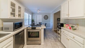 A kitchen with white cabinetry, a microwave, an oven, and a coffee maker. - Modern 4 Bedroom pets welcome sleeps 8 (Greensboro)
