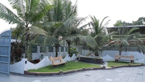 Ein gepflasterter Innenhof mit Palmen, einer Holzbank und einem kleinen Gartenbereich.
