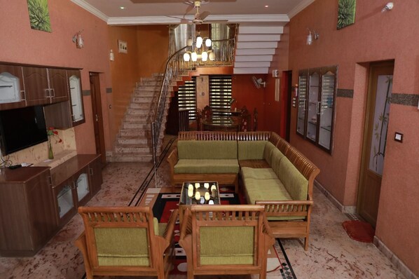 Un grand espace de vie comprenant un escalier, un ensemble de canapés, un téléviseur et une table à manger.