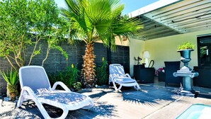 A poolside area with two lounge chairs, a palm tree, and a small table with a lamp. - Amazing home in St Victor la Coste (St Victor la Coste)