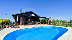 Ein modernes Haus mit Swimmingpool, Sitzgelegenheiten im Freien und einer Grillzone.