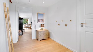 A hallway with wooden flooring, a white door, and a wall-mounted lamp. - 4 bedroom amazing home in Væggerløse (Væggerløse)