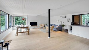 A spacious living area with a dining table, seating, a sofa, and a kitchen area with a large window. - 4 bedroom amazing home in Væggerløse (Væggerløse)