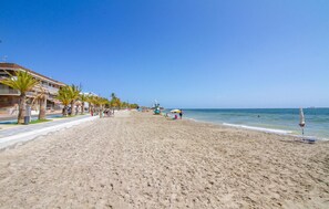 A beach with palm trees, a lifeguard tower, and a clear blue sky. - 2 bedroom cozy apartment in San Pedro del Pinatar (San Pedro del Pinatar)