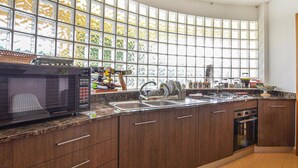 A kitchen with a large window, a microwave, a sink, and cabinets. - Beautiful apartment in S. Croce Camerina RG (S. Croce Camerina RG)