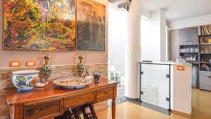 A modern kitchen with a wooden dining table, decorative vases, and a large abstract painting. - Beautiful apartment in S. Croce Camerina RG (S. Croce Camerina RG)