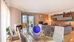 A modern living room with a glass dining table, grey sofas, and a stone accent wall. - Beautiful apartment in S. Croce Camerina RG (S. Croce Camerina RG)