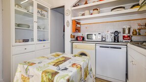 Cocina compacta con lavadora, microondas y cafetera sobre la encimera.