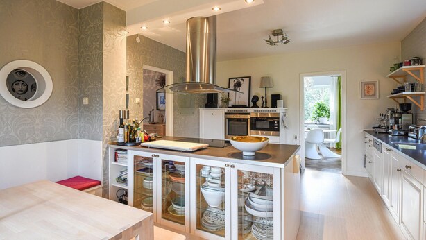 A modern kitchen with a central island, built-in oven, and a large stainless steel range hood. - Stunning home in Göteborg with sauna (Göteborg)