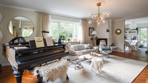 A living room with a grand piano, a fireplace, a sofa, and a chandelier. - Stunning home in Göteborg with sauna (Göteborg)