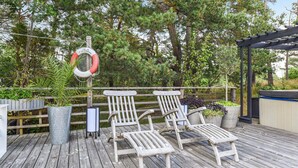 A wooden deck with lounge chairs and planters, surrounded by trees and a pergola. - Stunning home in Göteborg with sauna (Göteborg)
