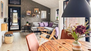 Een moderne woonkamer met een bank, een ronde houten tafel en een grote zwarte lamp.