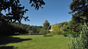 Un área verde bien cuidada con una carpa blanca, un arco de fútbol y un edificio con muros cubiertos de hiedra.