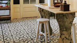Una cucina con isola in marmo, uno sgabello di legno e un pavimento decorato.