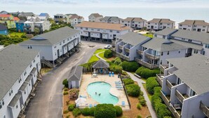 A residential complex with a central swimming pool, multiple balconies, and a view of the sea. - Oceanview Townhouse w/ Pool - Newly Renovated (Surf City)