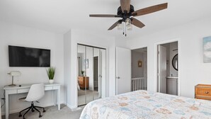 A bedroom with a bed, desk, chair, ceiling fan, and a TV. - Oceanview Townhouse w/ Pool - Newly Renovated (Surf City)