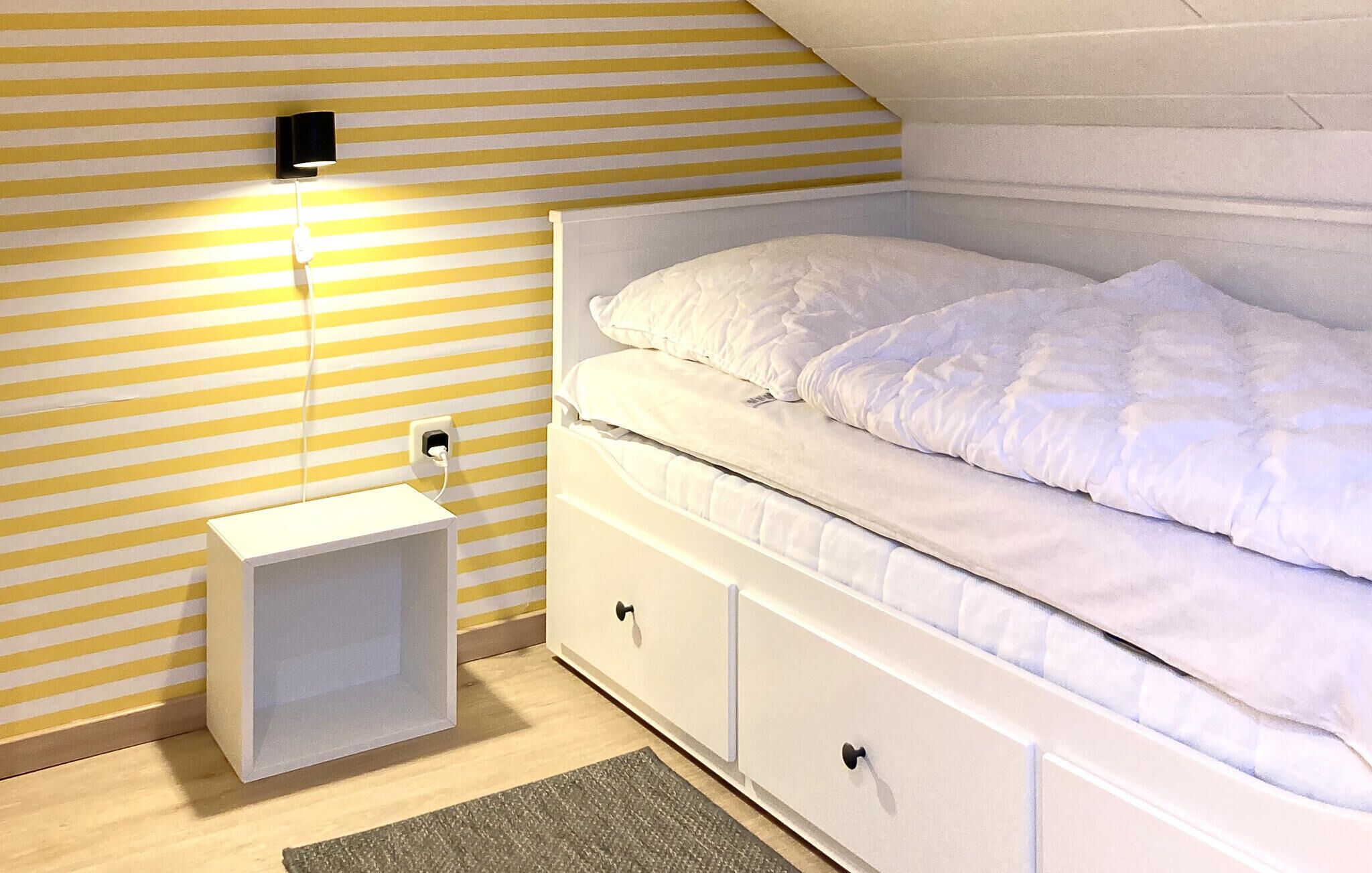 Un dormitorio con cama, almacenamiento junto a la cama, mesita de noche y lámpara de pared.